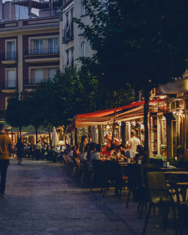 Calle peatonal del centro de Sevilla al anochecer, con terrazas iluminadas